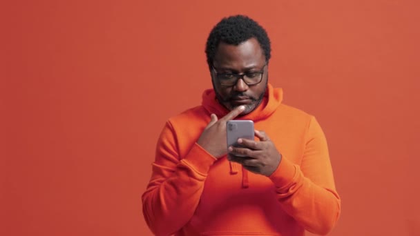 Reifer Afrikanischer Mann Blättert Orangefarbenen Studio Telefon — Stockvideo
