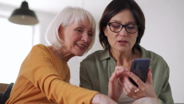 Sorrindo Mulheres Meia Idade Falando Olhando Para Telefone Sofá Casa — Vídeo de Stock