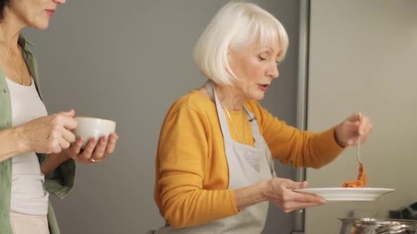 Θετική Ώριμη Γυναίκα Βάζει Μακαρόνια Ένα Πιάτο Στην Κουζίνα — Αρχείο Βίντεο