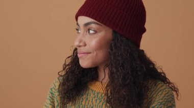 Neşeli Afrikalı kıvırcık saçlı kadın bej stüdyoda sessizlik jesti yapıyor.