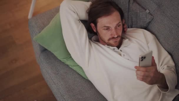 Selbstbewusster Langhaariger Der Hause Auf Dem Sofa Auf Das Handy — Stockvideo