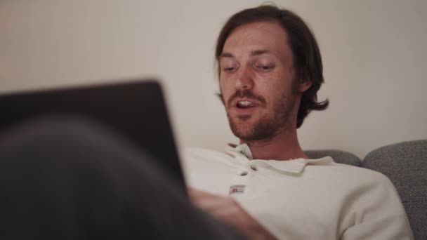 Glücklicher Langhaariger Mann Arbeitet Laptop Während Hause Auf Dem Sofa — Stockvideo