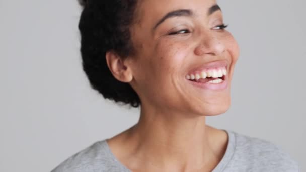 笑うアフリカの女性でTシャツを着てカメラをポーズでグレーのスタジオ — ストック動画