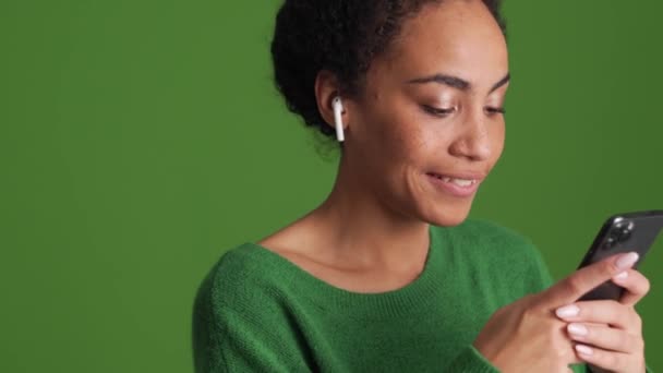 Glimlachende Afrikaanse Vrouw Groen Shirt Sms Telefoon Een Koptelefoon Groene — Stockvideo