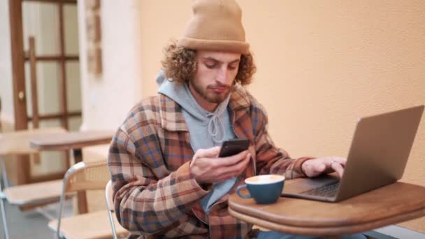 Komoly Göndör Hajú Férfi Nézi Telefont Sms Laptoppal Kávézó Szabadban — Stock videók