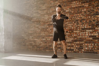 Orta yaşlı, gülümseyen, sakallı, akıllı adam içeride durup nabzını kontrol ediyor.