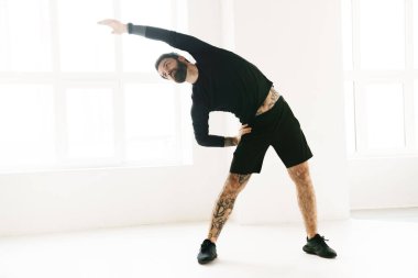 Kendine güvenen orta yaşlı beyaz sporcu, parlak bir odada egzersiz yapıyor.