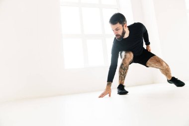 Kendine güvenen orta yaşlı beyaz sporcu, parlak bir odada egzersiz yapıyor.