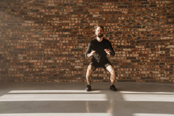 Kendinden emin orta yaşlı beyaz sporcu, parlak bir odada zıplıyor.