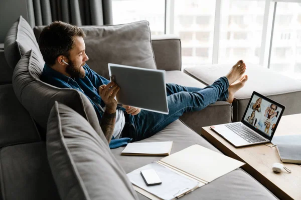 Homem Barbudo Fazendo Chamada Conferência Laptop Enquanto Sentado Sofá Casa — Fotografia de Stock