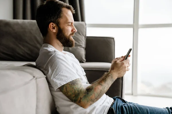 Bearded European Man Using Mobile Phone While Sitting Floor Home — Stock Photo, Image