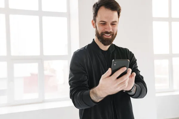 Smiling Young Brunette White Man Sportswear Standing Indoors Looking Mobile — Stock Photo, Image