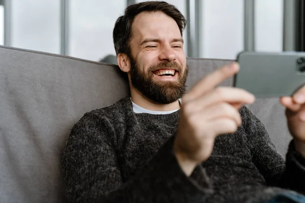 Homem Europeu Barbudo Usando Telefone Celular Enquanto Sentado Sofá Casa — Fotografia de Stock