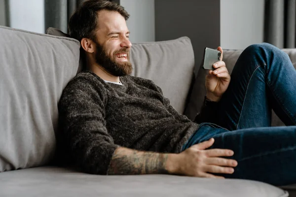 Homem Europeu Barbudo Usando Telefone Celular Enquanto Sentado Sofá Casa — Fotografia de Stock