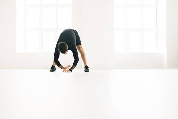 Confident mid aged white sportsman exercising in a bright room stretching