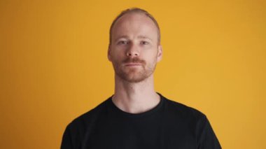 Sarı stüdyoda kafasını sallayan konsantre bir adam.