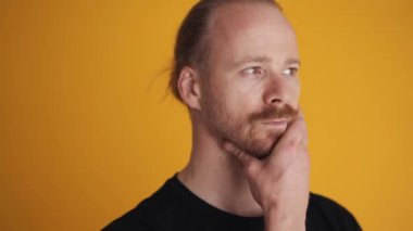 Düşünceli bir adam sarı stüdyoda bir şeyler düşünüyor.