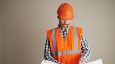 Ciddi müteahhit gri stüdyodaki projeye bakıyor.