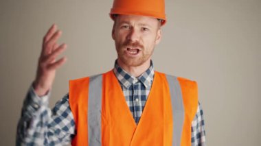 Gri stüdyoda kameraya bağıran konsantre müteahhit.