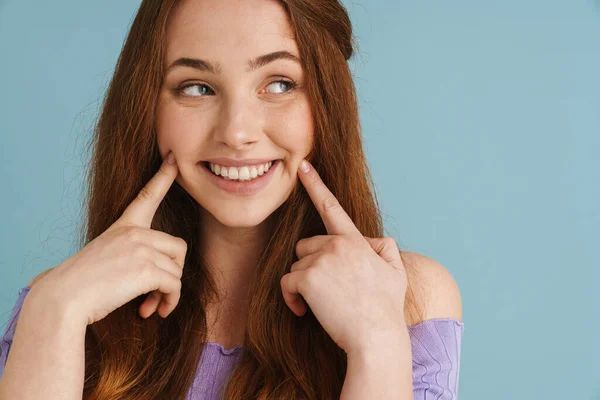 Молода Імбирна Жінка Посміхається Вказує Пальці Щоки Ізольовані Синьому Фоні — стокове фото