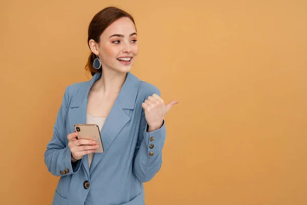 Mujer Jengibre Joven Señalando Con Dedo Lado Mientras Utiliza Teléfono —  Fotos de Stock