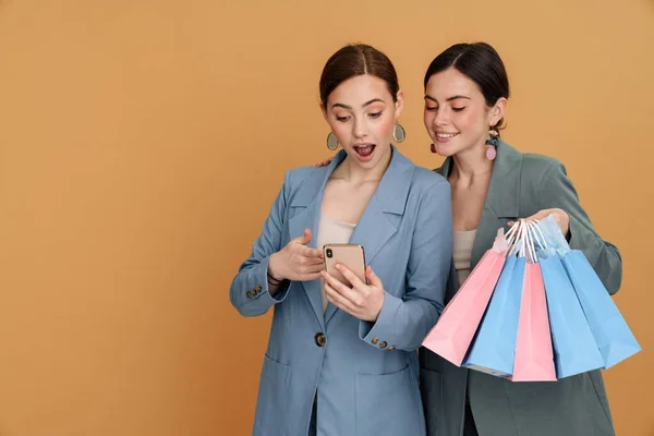 Joven Dos Mujeres Sosteniendo Bolsas Compras Utilizando Teléfono Celular Aislado — Foto de Stock