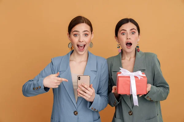 Молоді Дві Жінки Тримають Подарункову Коробку Використовують Мобільний Телефон Ізольовано — стокове фото