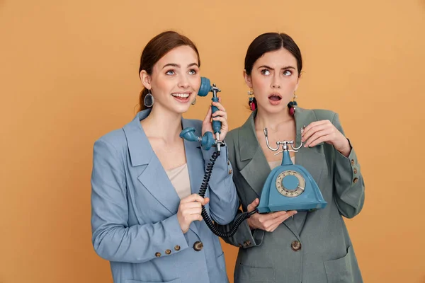 Młode Dwie Kobiety Kurtce Pozowanie Retro Telefon Izolowane Żółtym Tle — Zdjęcie stockowe