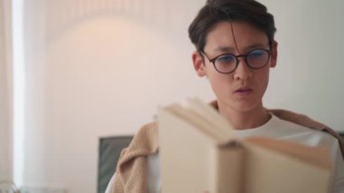 Kendinden emin Asyalı adam evde kitap okuyor.