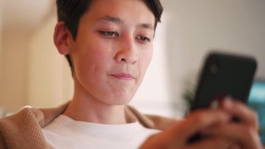 Yakışıklı Asyalı adam evden cep telefonuna bakıyor.