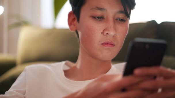 Konzentrierte Brünette Asiatische Mann Sms Telefon Auf Dem Sofa — Stockvideo