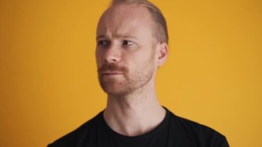 Memnun olmayan adam sarı stüdyonun kenarlarına bakıyor.