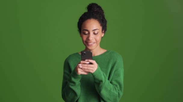 Mulher Africana Sorridente Camisa Verde Digitando Por Telefone Estúdio Verde — Vídeo de Stock