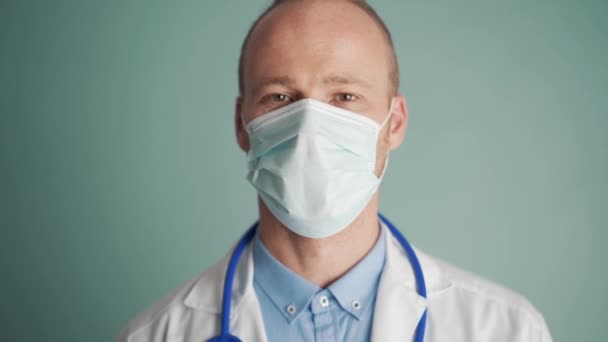 Pensive Γιατρός Θέσει Προστατευτική Μάσκα Προσώπου Στο Μπλε Στούντιο — Αρχείο Βίντεο