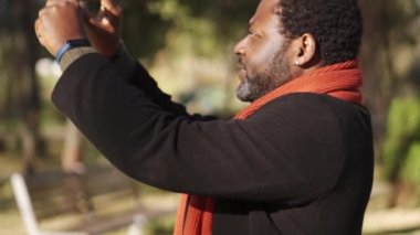 Kendine güvenen Afrikalı adam parkta doğanın fotoğrafını çekiyor.