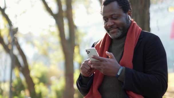 Hombre Africano Positivo Auriculares Mirando Teléfono Parque Aire Libre — Vídeo de stock