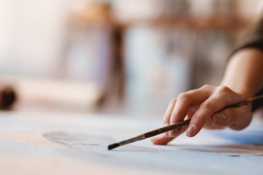 Bir sanat stüdyosunun zemininde otururken kadın el sanatları ressamı elinde fırça tutuyordu.
