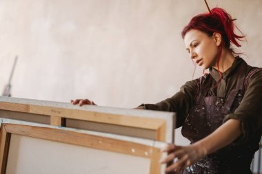 Sanat atölyesindeki genç beyaz kadın ressam, fikir üretmek için dizüstü bilgisayar kullanıyor.