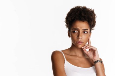 Young black woman in tank top frowning and looking aside isolated over white background