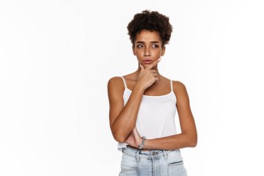 Young black woman in tank top frowning and looking aside isolated over white background