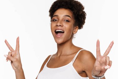 Young black woman in tank top smiling and gesturing at camera isolated over white background