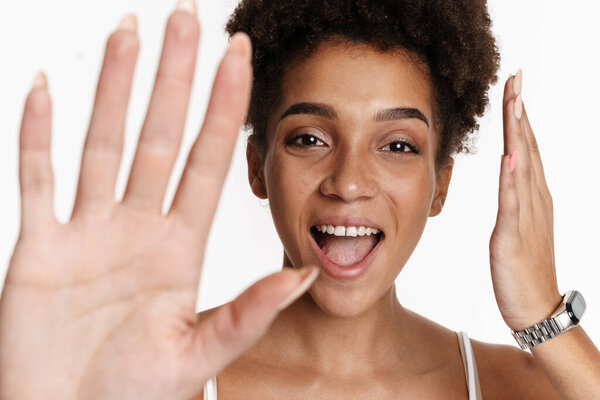 Young black woman in tank top laughing and gesturing at camera isolated over white background