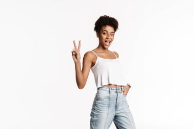 Young black woman in tank top smiling and gesturing at camera isolated over white background