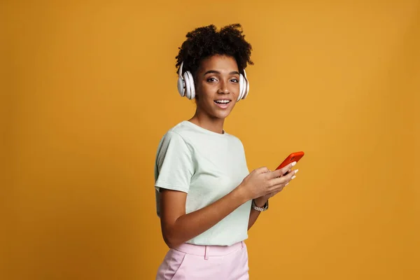 Young Black Woman Listening Music Headphones Cellphone Isolated Yellow Background — Foto Stock