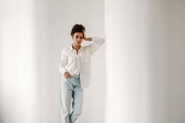 Young black woman leaning on wall and looking at camera indoors