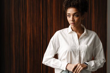 Young black woman standing and looking aside indoors
