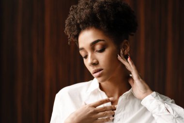 Young black woman posing and looking downward indoors