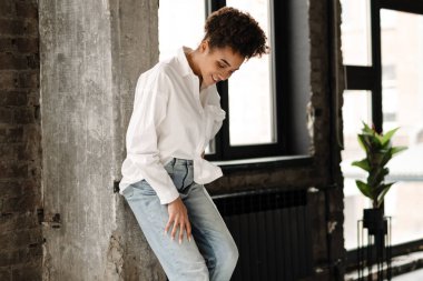 Young black woman laughing while leaning on wall indoors