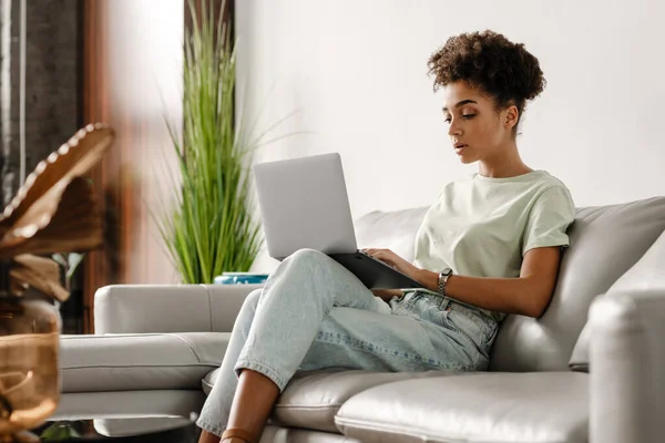 Wanita Hitam Muda Bekerja Dengan Laptop Sambil Duduk Sofa Rumah — Stok Foto