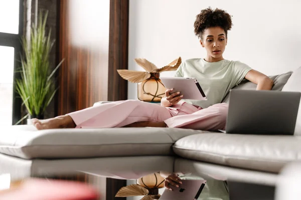 Young Black Woman Using Tablet Computer While Working Laptop Home — Stockfoto